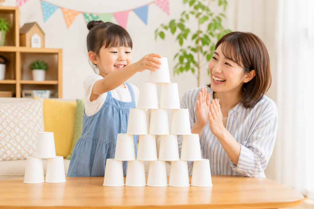 親子で白い紙コップを積み上げ、紙コップタワー作りを楽しんでいる様子